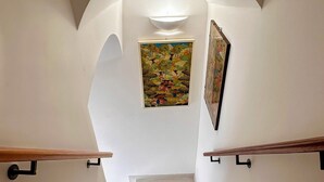 Escada com paredes brancas e um quadro de uma paisagem.