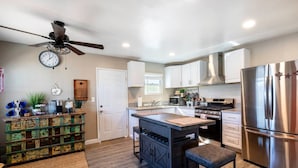 A modern kitchen with a central island, stainless steel appliances, and a ceiling fan.