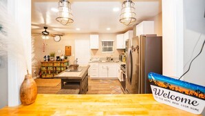 A modern kitchen with white cabinets, a stainless steel refrigerator, and a wooden island.