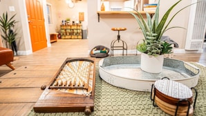 A room with a wooden floor, a small table with a plant, a decorative tray, and a traditional Japanese game.