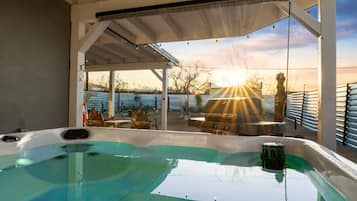 Ein Whirlpool mit Blick auf den Sonnenuntergang und ein Grill.