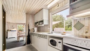 A modern kitchen with white cabinetry, a built-in oven, and a window overlooking a garden. - Lovely home in Nykøbing Sj with WiFi (Nykøbing Sj)