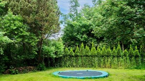 A trampoline in a grassy yard surrounded by dense trees and shrubs. - Lovely home in Nykøbing Sj with WiFi (Nykøbing Sj)