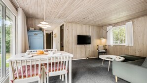 A cozy room with a wooden ceiling, a dining table with chairs, a sofa, a television, and a window with curtains. - Lovely home in Nykøbing Sj with WiFi (Nykøbing Sj)