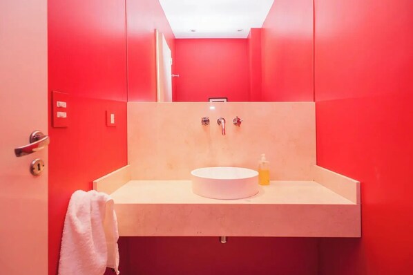 A bathroom with a red interior, a white sink, and a towel hanging on the wall.