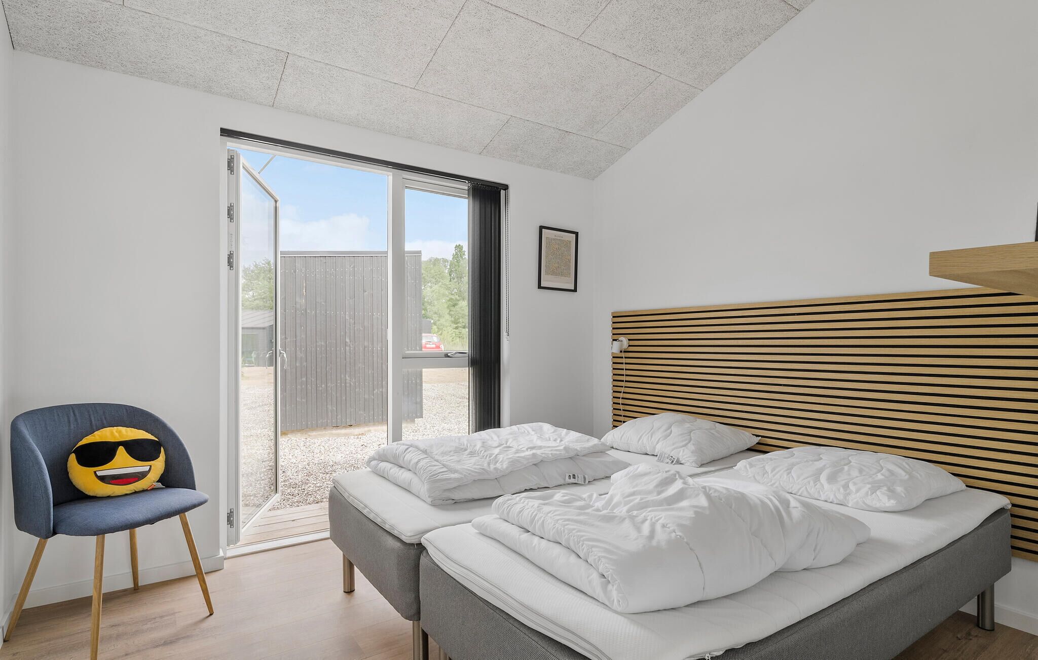 Un dormitorio con cama, una silla y vistas a través de un ventanal corredera.