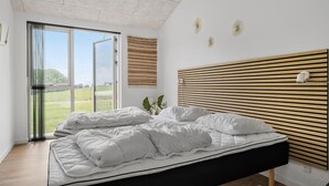A bedroom with a bed, a large window, and a wooden headboard. - Awesome home in Haderslev with sauna (Haderslev)