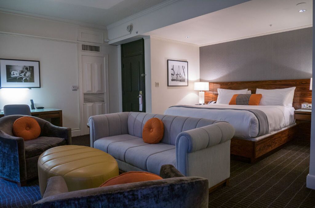 Une chambre d’hôtel avec un lit, deux fauteuils, un canapé et une petite table.