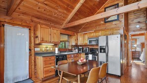 Cocina rústica con una mesa de comedor, sillas y un refrigerador.