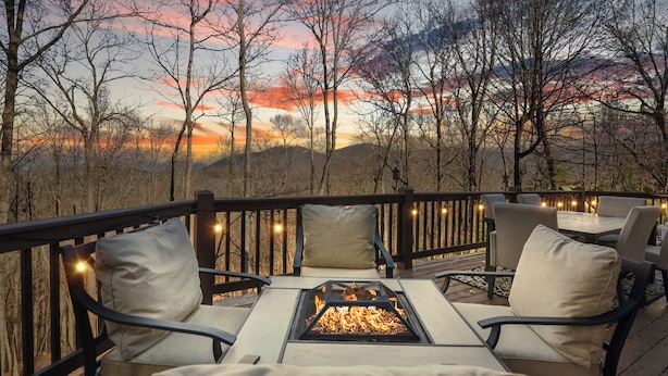 Una terraza con asientos al aire libre, una chimenea y vistas a un paisaje boscoso.