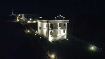 Un edificio de dos pisos con fachada simétrica, iluminado por luces exteriores.