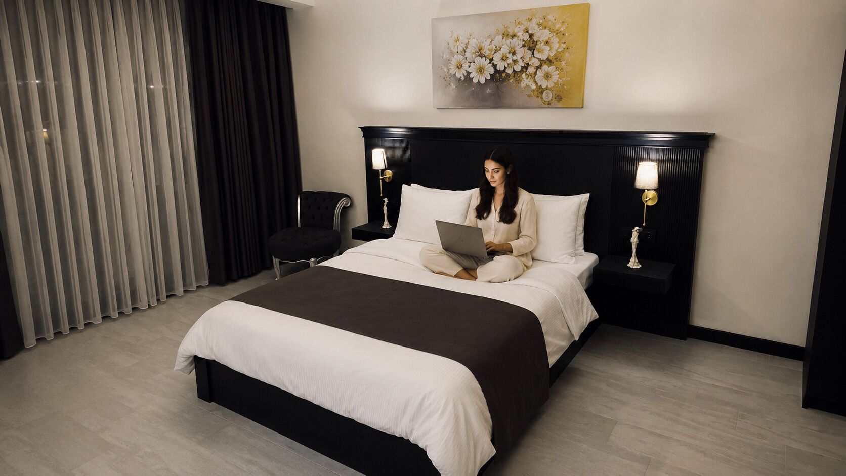 Quarto de hotel com uma cama grande, mesa de apoio, cadeira, escrivaninha e um quadro na parede.