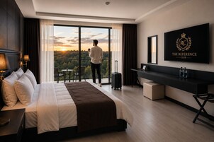 A hotel room with a bed, a desk, a TV, and a view of the outdoors.