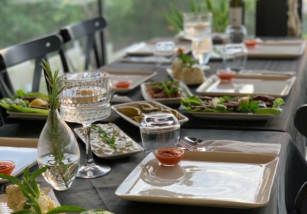 Una mesa de comedor dispuesta con platos, vasos y un pequeño florero con follaje.