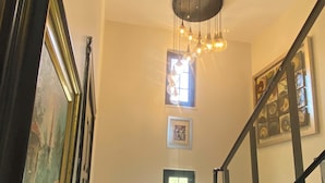A staircase with a glass railing, a chandelier, and a framed picture on the wall. - The Reference Club Restaurant & Accommodation (Luleburgaz)