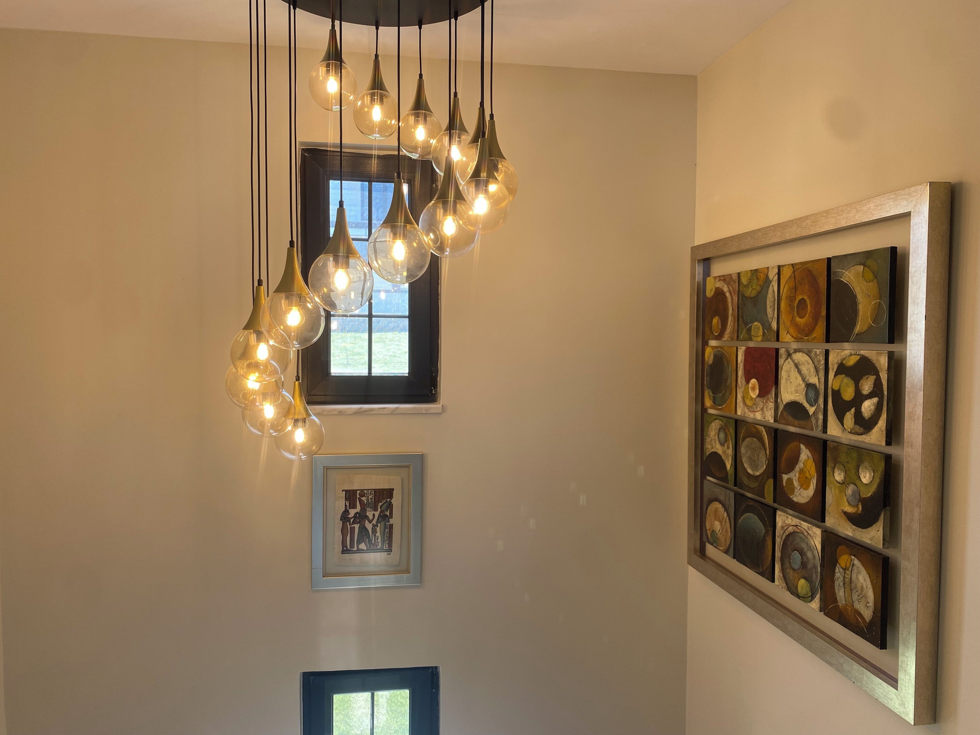 Una habitación con una lámpara moderna, una obra de arte enmarcada y un ventanal.