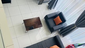 A modern living room with a black sofa, a wooden coffee table, and a staircase leading to an upper floor. - Embassy garden ebs legend luxury studio  (Accra)