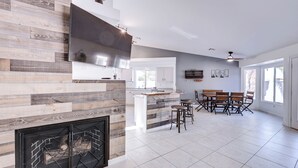 A modern kitchen with a built-in fireplace, a dining area with wooden furniture, and a large window providing natural light.