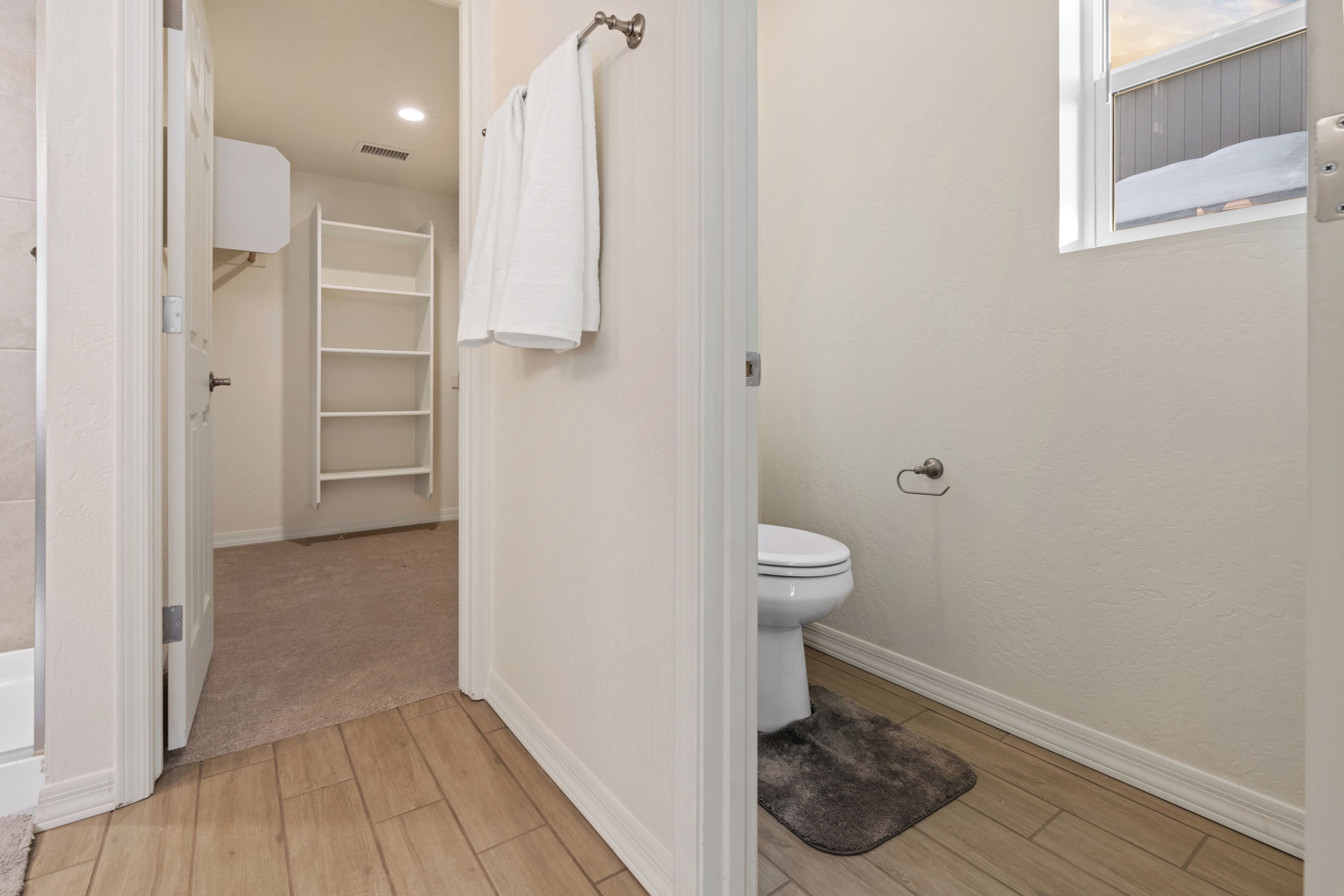 Un baño con inodoro, toallero, zona de ducha y ventana con vistas.