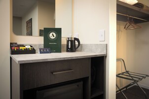 Habitación de hotel con kitchenette, que incluye una cafetera, un panel de menú y un juego de artículos de aseo.
