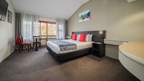 A bedroom with a bed, bedside table, chair, and a window with curtains. -  Carnmore Hotel Lower Hutt (Lower Hutt)