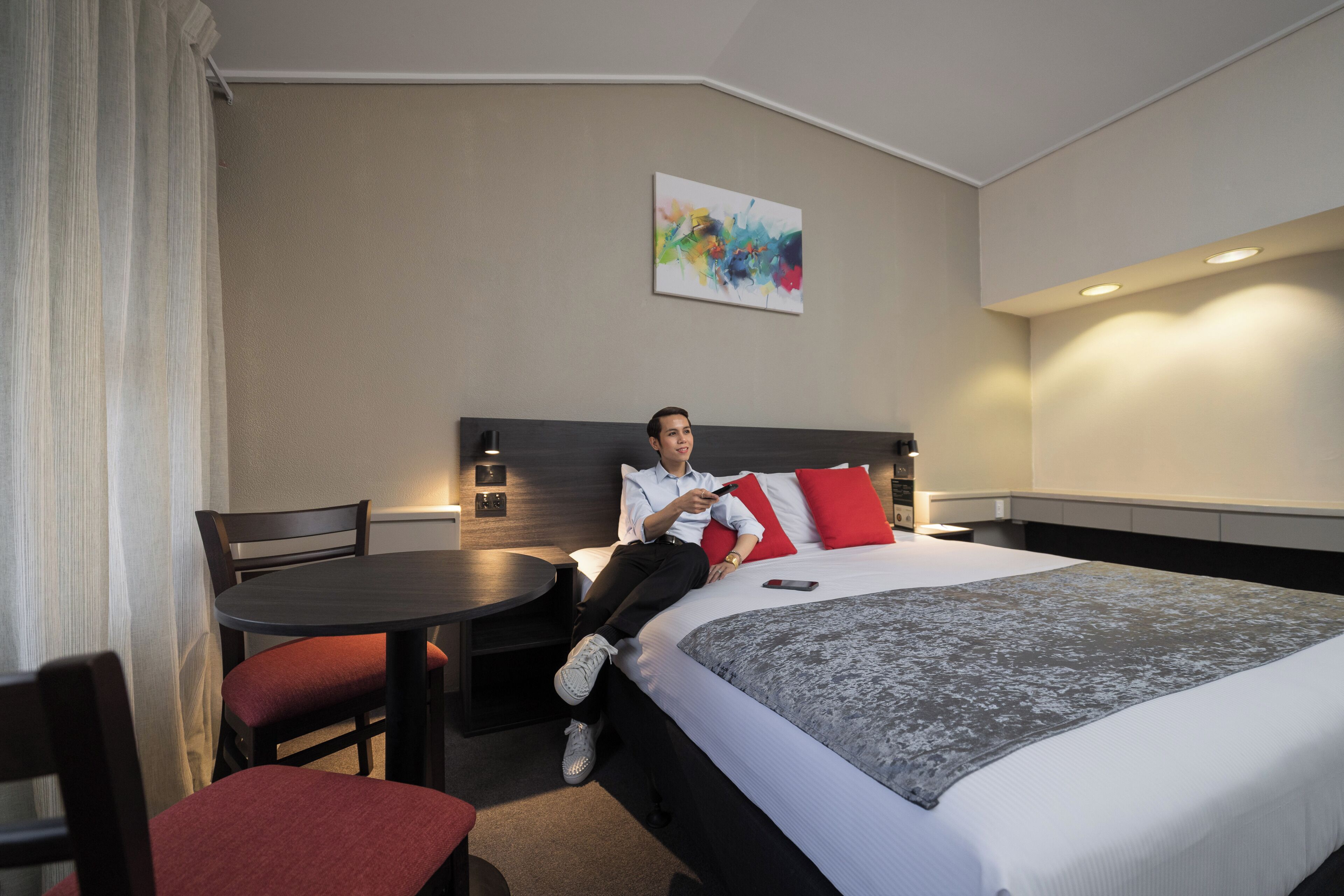 Ein Hotelzimmer mit einem Bett, einem Schreibtisch, einem Stuhl und einem Bild an der Wand.