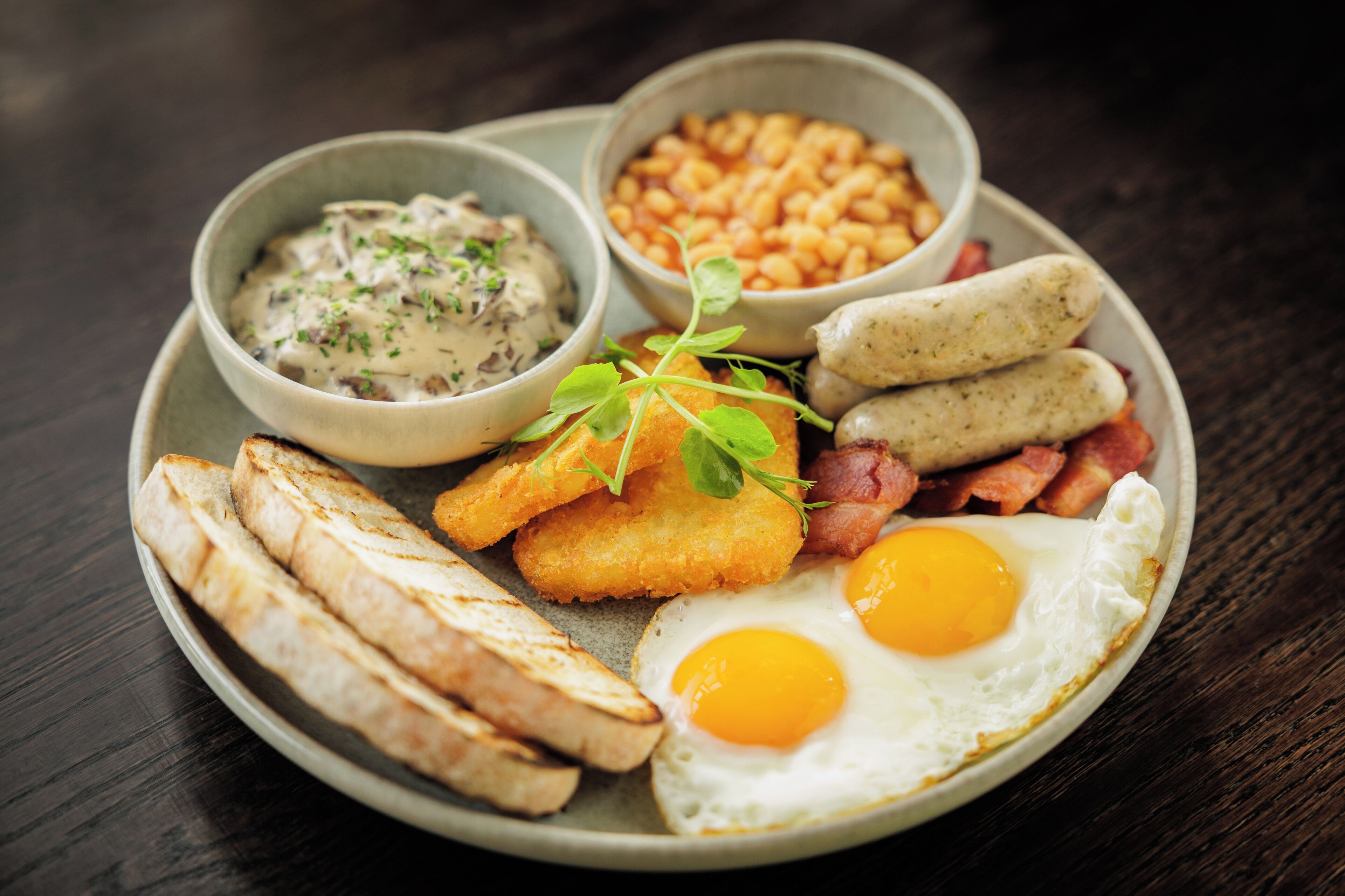 A plate with eggs, bacon, sausages, beans, and toast.