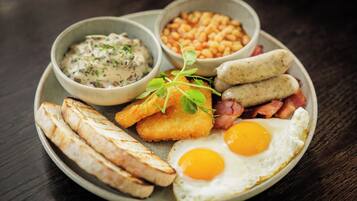 A plate with eggs, bacon, sausages, beans, and toast.