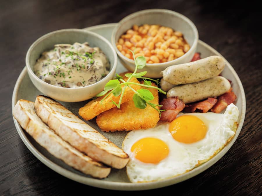 A plate with eggs, bacon, sausages, beans, and toast.