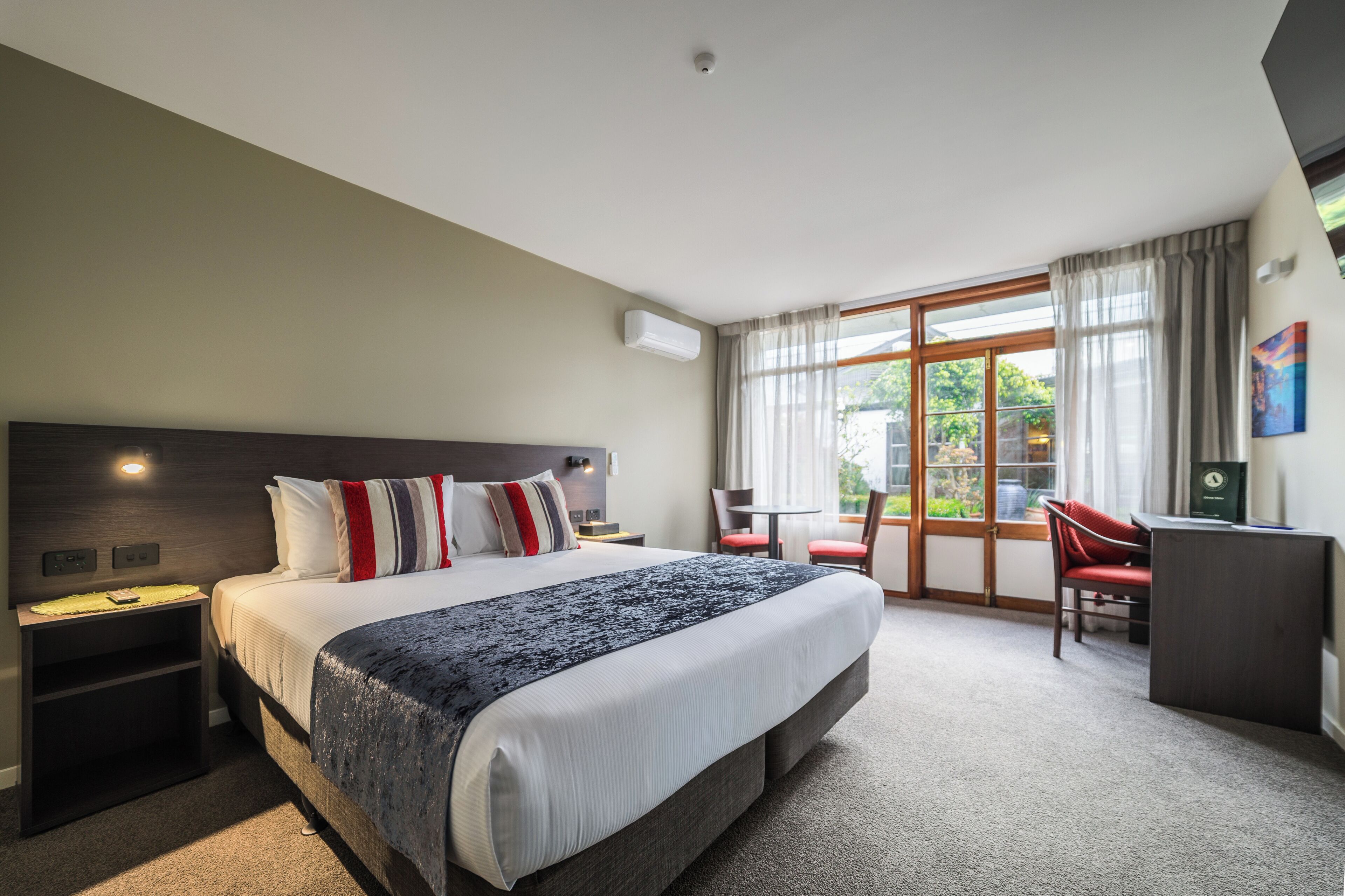 Een hotelkamer met een groot bed, een bureau en uitzicht op de omgeving.