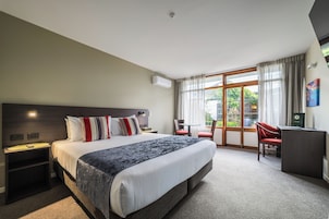 A hotel room with a large bed, a desk, and a view of the outdoors.