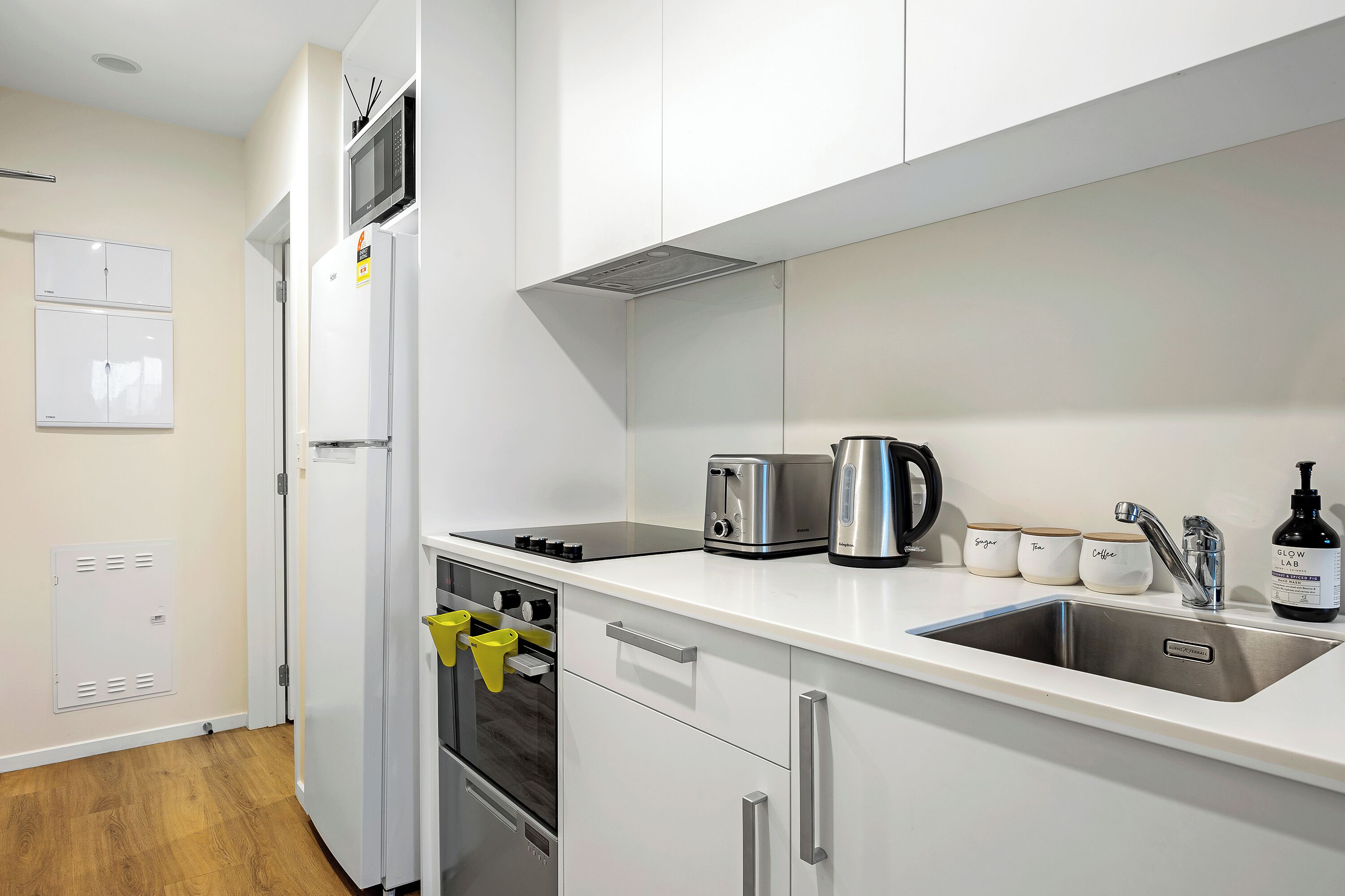 Una cocina moderna con armarios blancos, electrodomésticos de acero inoxidable, un fregadero y un tostador.