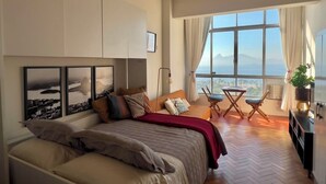 Ein Schlafzimmer mit Bett, Schreibtisch und Meerblick.
