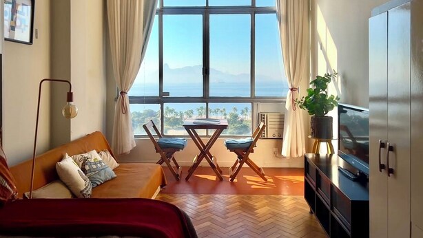 Ein Zimmer mit Bett, Fernseher, Tisch mit Stühlen und einem großen Fenster mit Aussicht.