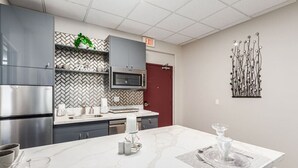 Una cocina moderna con electrodomésticos de acero inoxidable, salpicadero de baldosas tipo espiga y una isla de mármol.