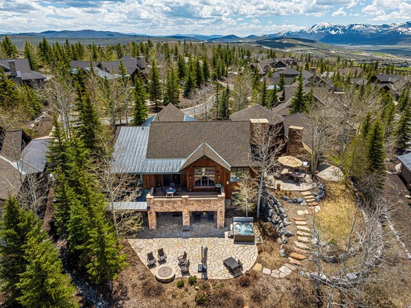 A large house with a stone patio, outdoor seating, and a hot tub.