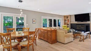 A spacious living area with a dining table, chairs, a sofa, a TV, and a fireplace.