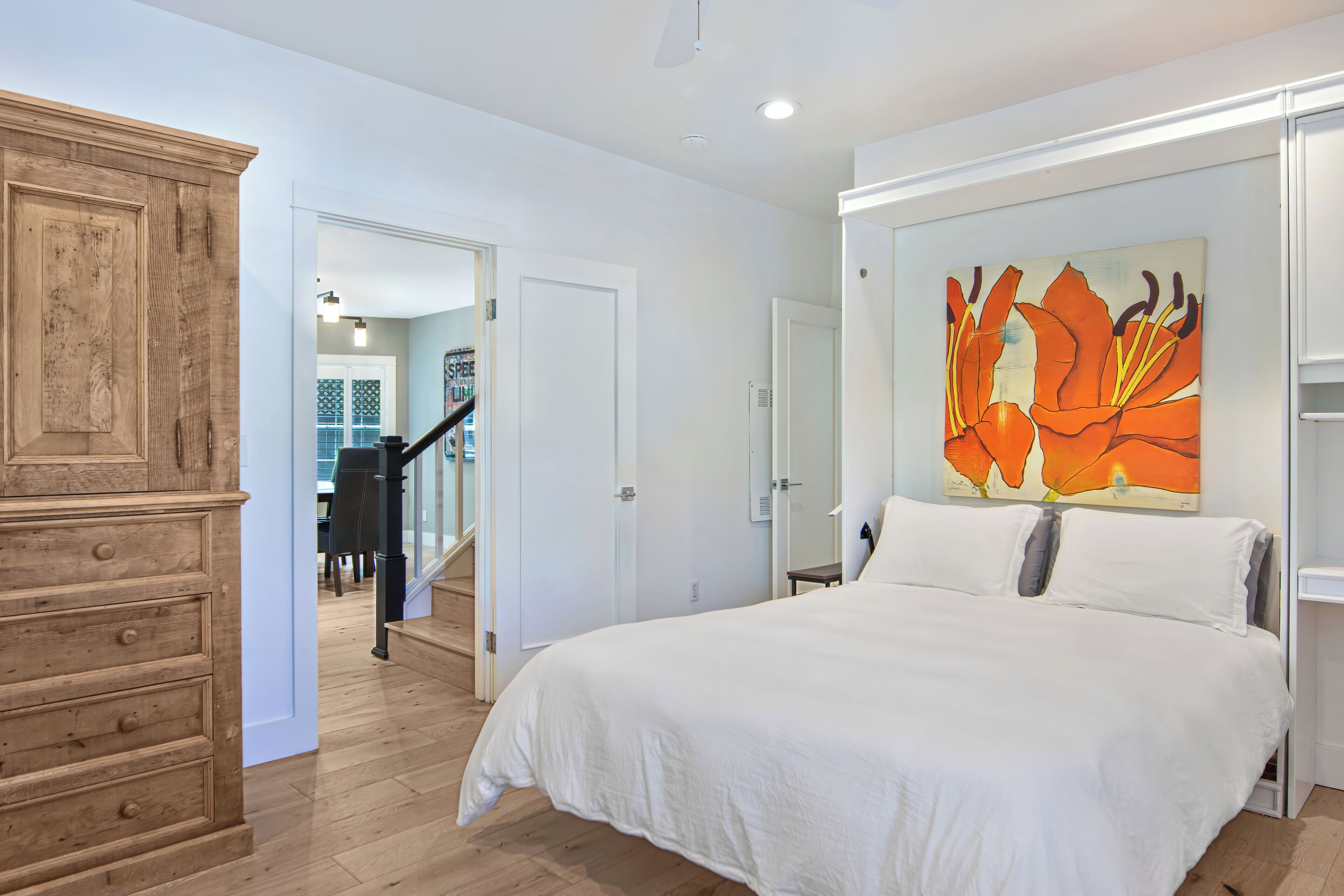 Un dormitorio con una cama grande, un aparador de madera y un cuadro en la pared.