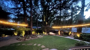 A well-maintained backyard with a paved patio, a lawn, and string lights.