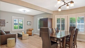 A spacious living area with a dining table, chairs, a sofa, and a cabinet.