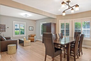 Uma sala ampla com uma mesa de jantar, cadeiras, um sofá e um armário.