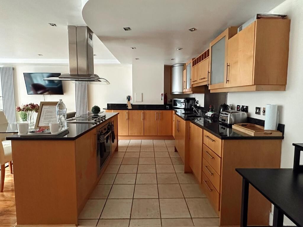A modern kitchen with wooden cabinets, a central island, and a built-in stove.