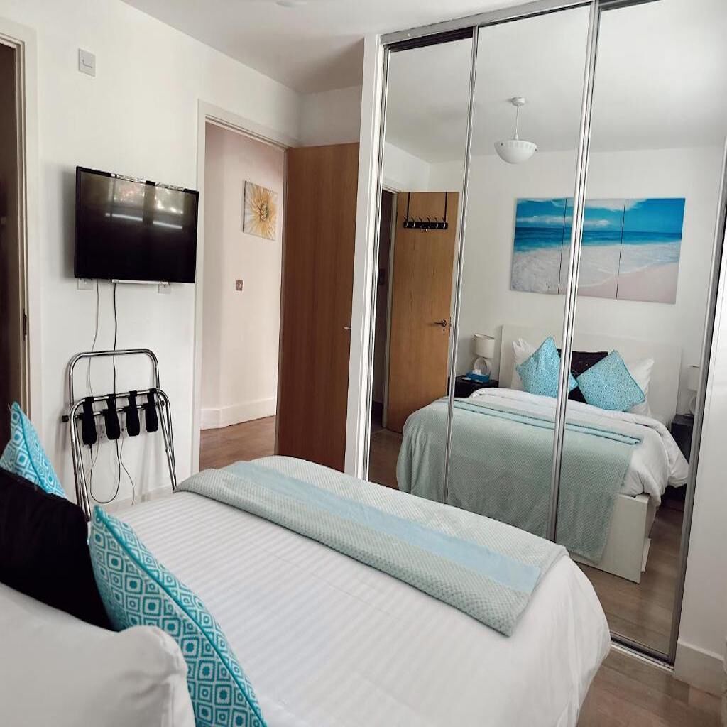 Ein Hotelzimmer mit Bett, Fernseher, Nachttisch und Spiegel.