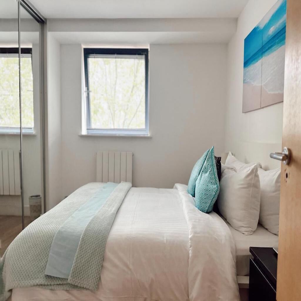 Un dormitorio con una cama, una ventana y un cuadro en la pared.