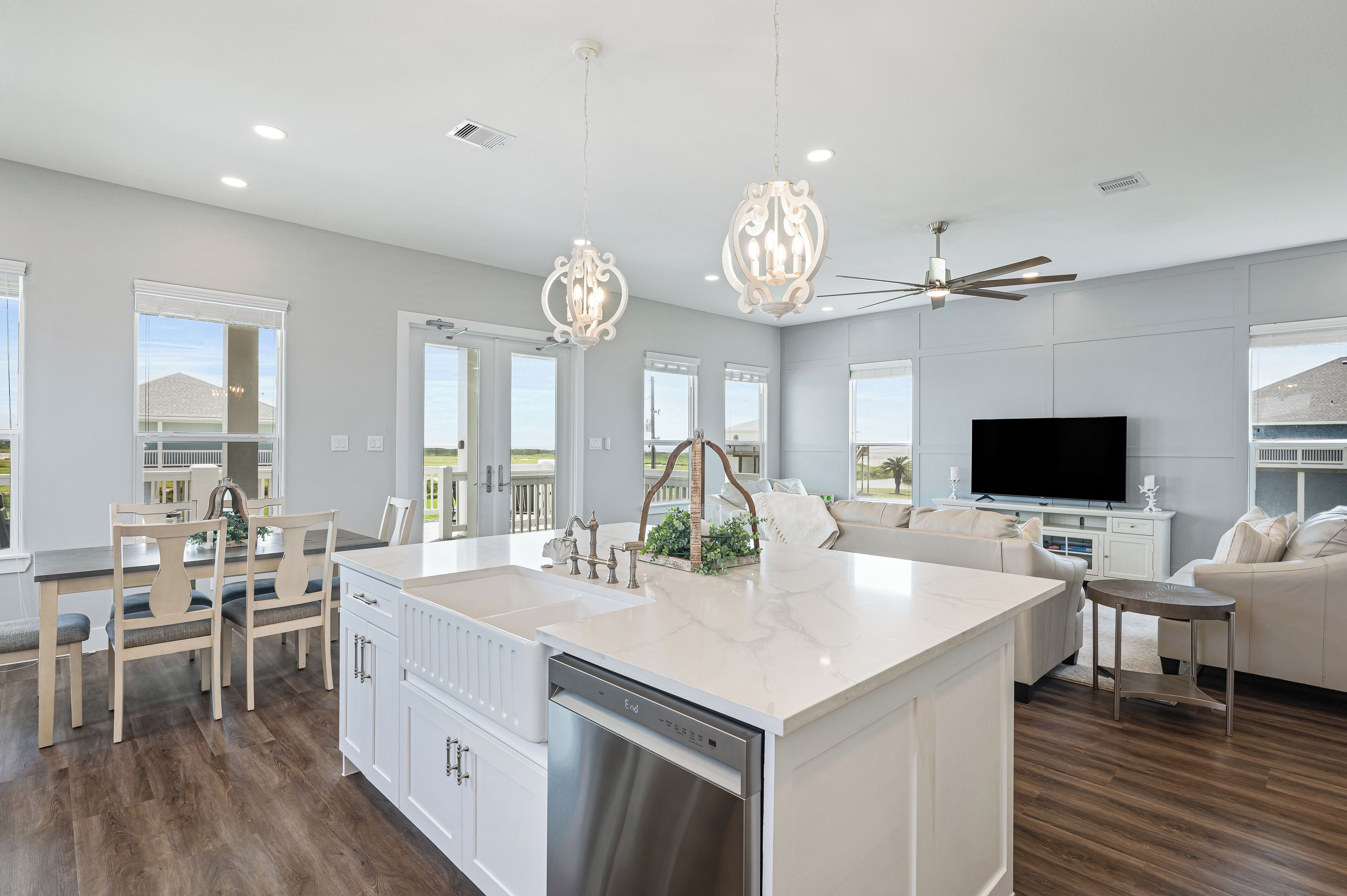 A modern kitchen with a large island, white cabinetry, and stainless steel appliances.