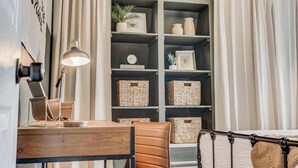 Ein Zimmer mit einem Holztisch, einem Ledersessel und einer Regalwand mit Körben und Dekoration.