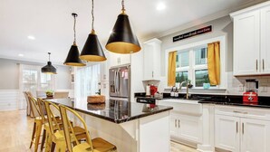 Une cuisine moderne avec des meubles blancs, un îlot central et un coin repas avec des chaises jaunes.