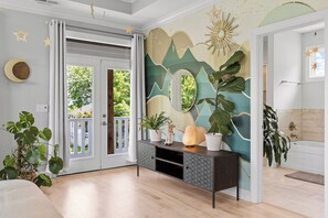 Une salle de bain moderne avec une baignoire, une douche et des toilettes. Un grand miroir est placé au-dessus du lavabo, et une plante en pot se trouve sur le comptoir.