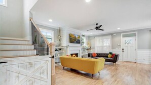 Un vaste espace de vie comprenant un escalier, une cheminée et un coin repas.