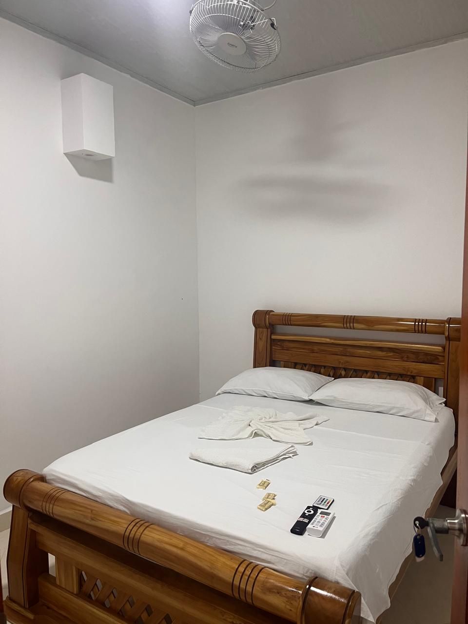 Una cama individual con cabecera de madera, colchón blanco y pared blanca.